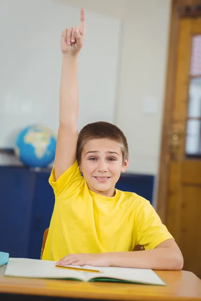 Alumno sonriente levantando la mano en un aula — Foto de Stock