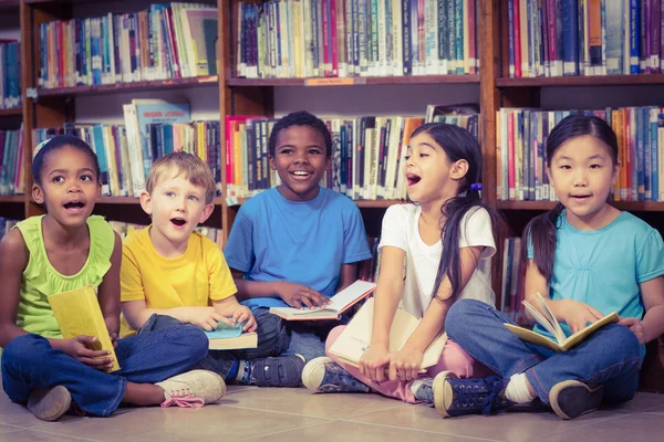 Alumnos sentados en el suelo y leyendo libros en la biblioteca — Foto de Stock