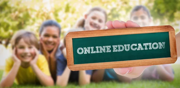 Online utbildning mot glada vänner i parken — Stockfoto