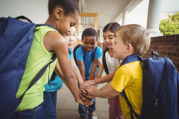 Pupils putting hands together at corridor — Stock Photo, Image