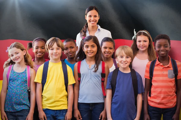 Composite image of cute pupils smiling at camera in the hall — Stock Photo, Image