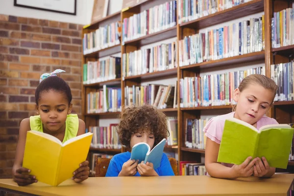 Alunos felizes lendo um livro de biblioteca — Fotografia de Stock