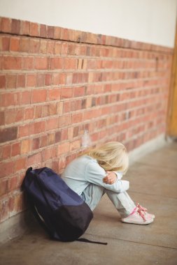 Sad pupil sitting alone on ground clipart