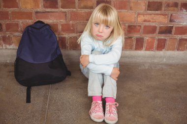 Sad pupil sitting alone on ground clipart