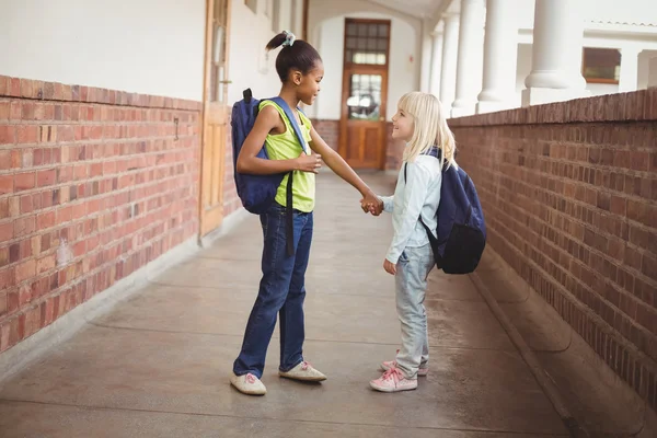Улыбающиеся ученики держатся за руки в коридоре — стоковое фото