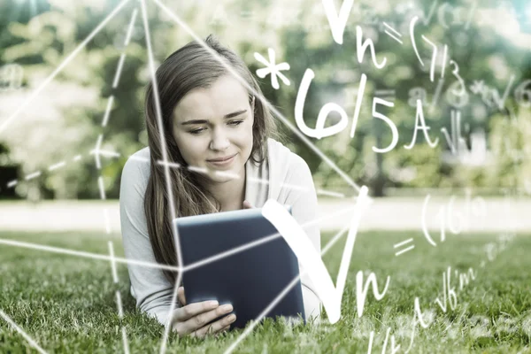 Student lying and using tablet pc — Stock Photo, Image