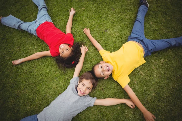 Ładny uczniów leżącego na trawa uśmiechający się — Zdjęcie stockowe