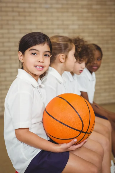 Estudante segurando basquete com outros jogadores — Fotografia de Stock