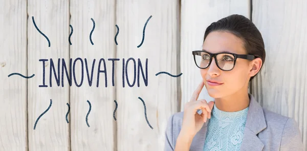 Innovation against stylish brunette thinking and smiling — Stock Photo, Image