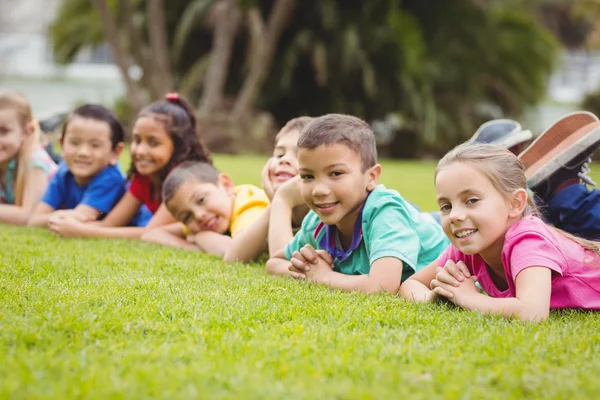 Cute pupils lying on grass outside — Stock Photo, Image