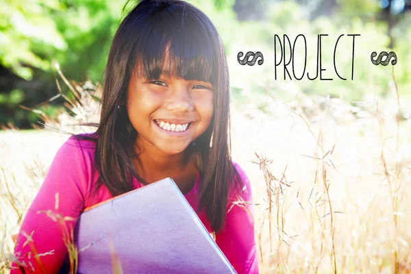 Projekt gegen niedliches kleines Mädchen beim Lesen im Park — Stockfoto