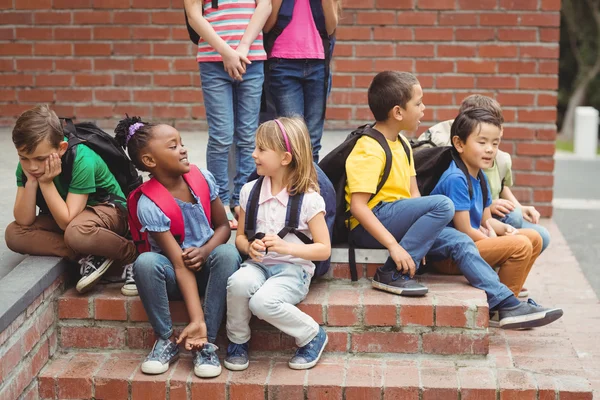 Niedliche Schüler sitzen auf Stufen vor der Tür — Stockfoto