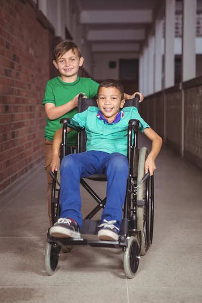 Uśmiechający się ucznia w wózku i przyjaciel obok niego — Zdjęcie stockowe