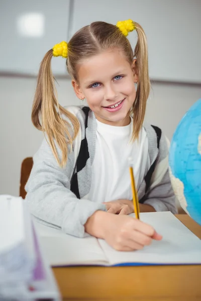 Aluno bonito trabalhando em sua mesa em uma sala de aula — Fotografia de Stock