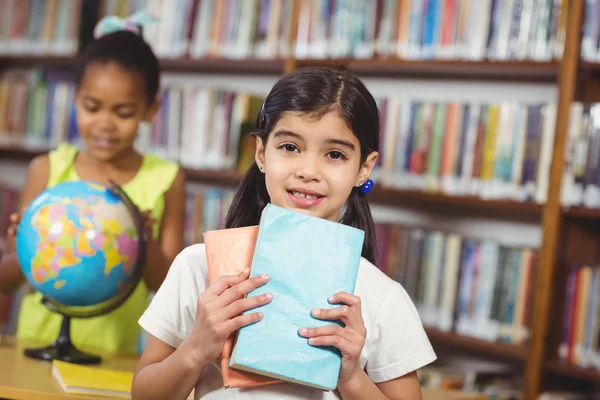 Alunno carino che tiene libri in biblioteca — Foto Stock