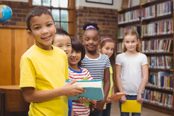 Leerlingen houden boeken van plank in bibliotheek — Stockfoto