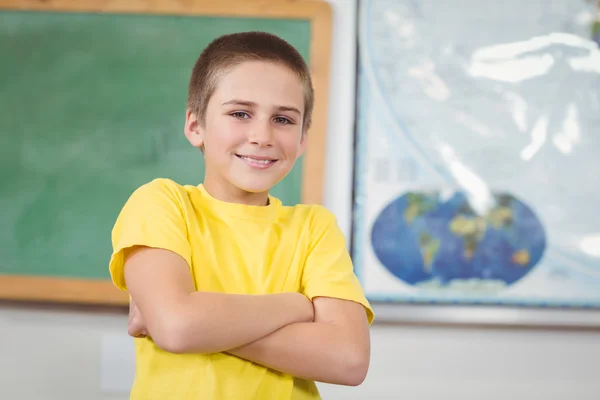 Pupilla sorridente con le braccia incrociate in un'aula — Foto Stock