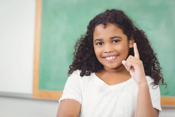 Lachende leerling verhogen hand in een klaslokaal — Stockfoto