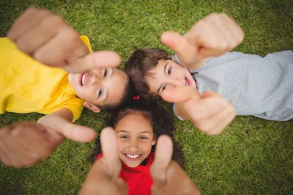 Schattig leerlingen liggend op gras glimlachen — Stockfoto
