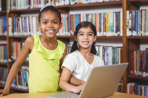 Alunos sorridentes usando laptop na biblioteca — Fotografia de Stock