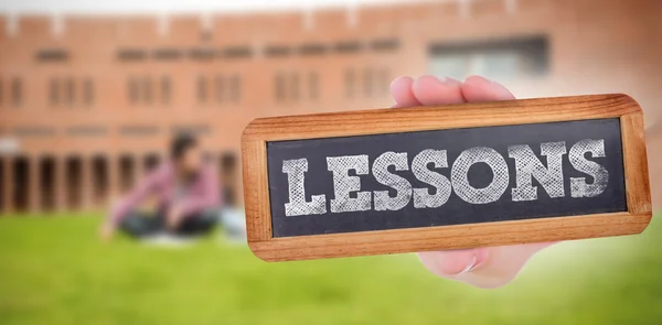 Word lessons and hand showing chalkboard — Stock Photo, Image