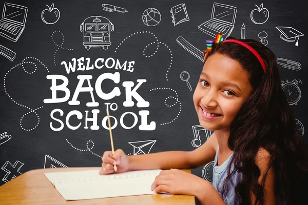 Leerling op haar bureau tegen schoolbord — Stockfoto