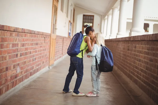 Cute pupils whispering secrets at corridor — Stock Photo, Image