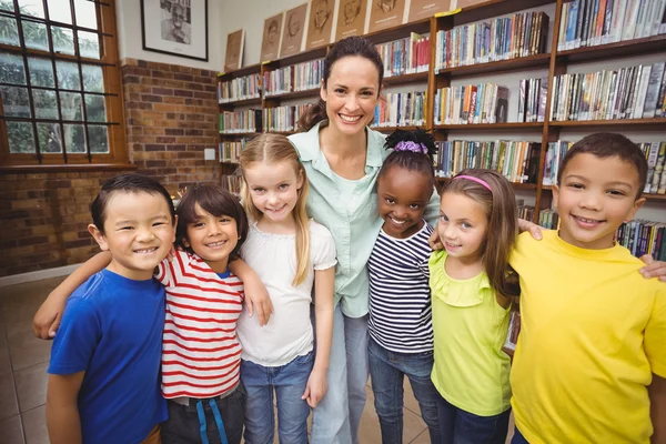 Leerlingen en leraar glimlachen op camera in bibliotheek — Stockfoto