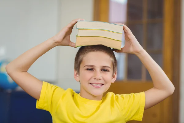 Smiling pupil balancing books — Stock Photo, Image