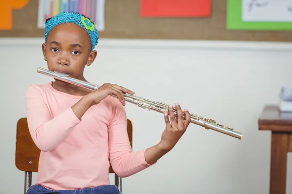 Élève mignon jouant de la flûte dans une salle de classe — Photo