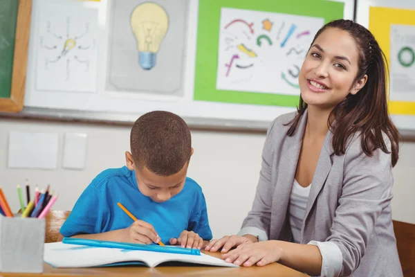 Bonito profesor ayudando a su alumno en su escritorio — Foto de Stock