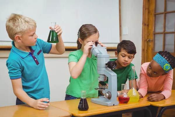 Estudiantes usando vasos de precipitados científicos y microscopio —  Fotos de Stock