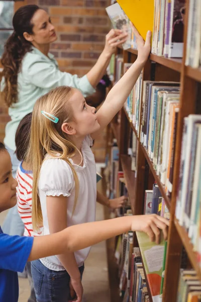 Pupils taking books from shelf in library — Stock Photo, Image