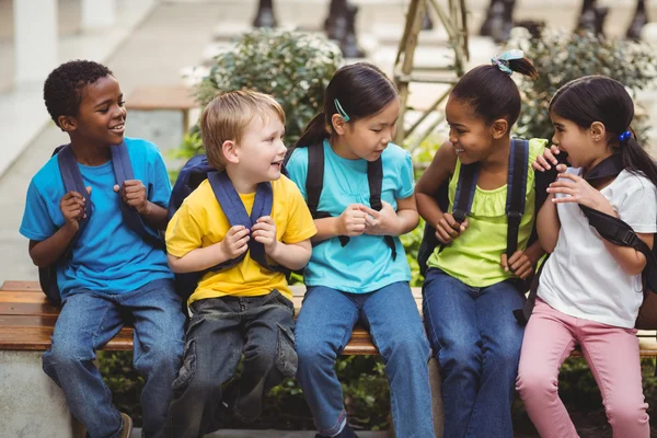 Pupils with schoolbags sitting on bench — Stock Photo, Image