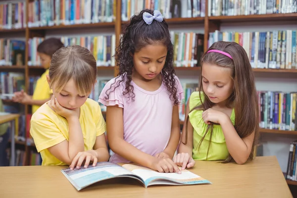 Pupils reading book together in library — Stock Photo, Image