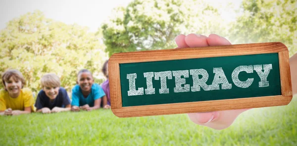 Word literacy and hand showing chalkboard — Stock Photo, Image