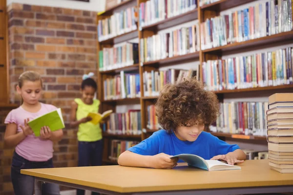 快乐的小学生阅读一本图书馆的书 — 图库照片