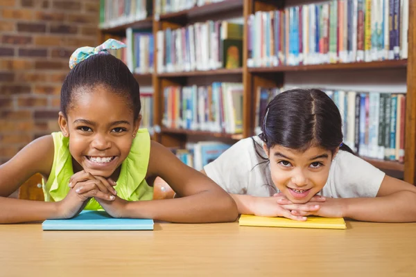 Alunos que se apoiam em livros na biblioteca — Fotografia de Stock