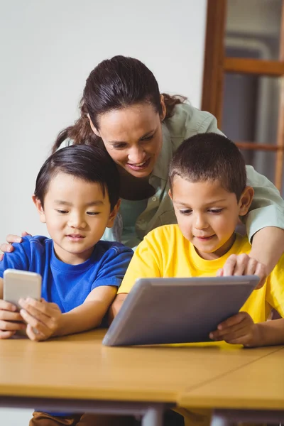 Élèves mignons en classe utilisant le téléphone et la tablette — Photo