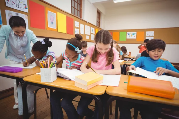 Alunos trabalhando em suas mesas em classe — Fotografia de Stock