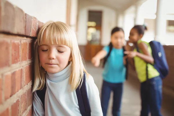 Aluno triste sendo intimidado por colegas de classe no corredor — Fotografia de Stock