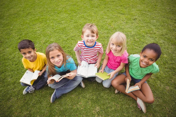 Smiling classmates sitting in grass Stock Image