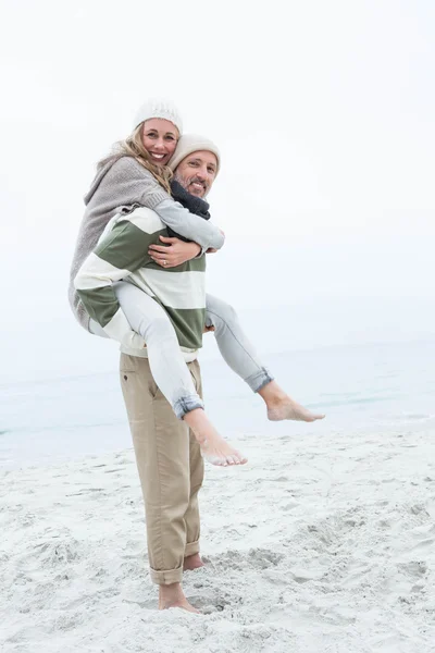 Muž dává partnera prasátko zpět na pláži — Stock fotografie