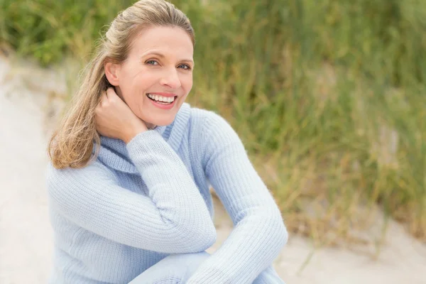 Mulher sorridente sentada na areia — Fotografia de Stock