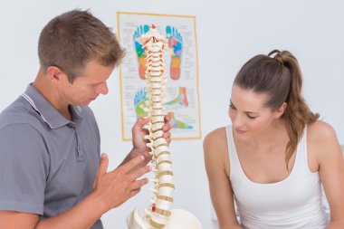 Doctor showing anatomical spine to patient clipart