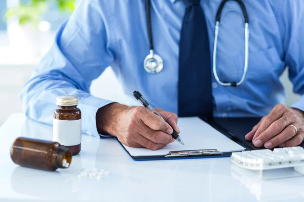 Male doctor writing on notepad — Stock Photo, Image