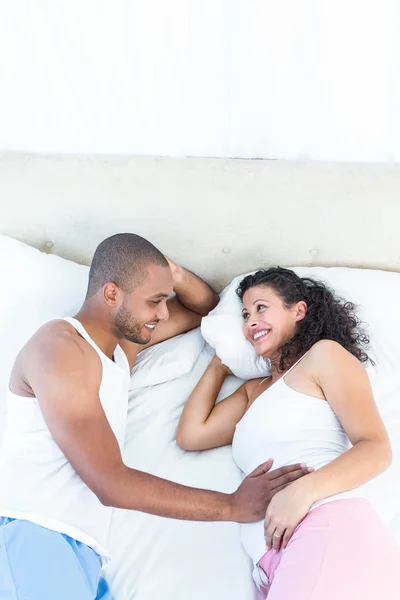 Femme enceinte souriante couchée sur le lit — Photo