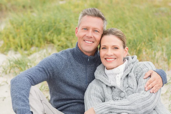 Sorrindo casal sentado na areia — Fotografia de Stock