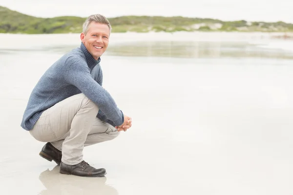 Man crouched down at the shore — Stock Photo, Image