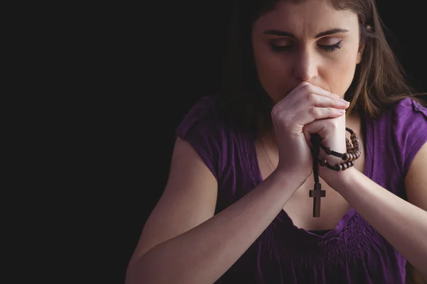 Woman praying with wooden rosary beads — Stock Photo, Image